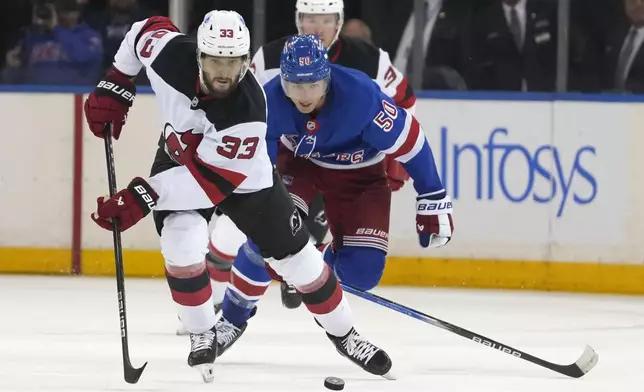 New Jersey Devils' Jakub Zboril, left, and New York Rangers' Will Cuylle, right, chase after the puck during the third period of an NHL preseason hockey game, Tuesday, Oct. 1, 2024, in New York. (AP Photo/Pamela Smith)