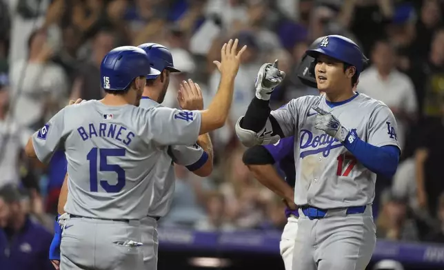 Los Angeles Dodgers' Austin Barnes (15) congratulates Shohei Ohtani (17) who crosses home plate after hitting a three-run home run off Colorado Rockies relief pitcher Anthony Molina in the sixth inning of a baseball game Friday, Sept. 27, 2024, in Denver. (AP Photo/David Zalubowski)