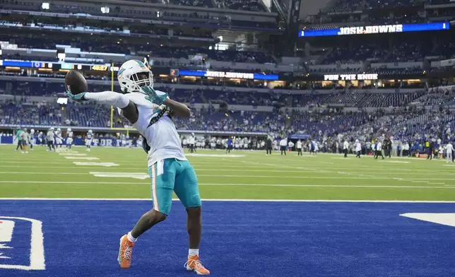 Miami Dolphins wide receiver Jaylen Waddle throws the ball to fans in the stands as he warms up before the start of an NFL football game against the Indianapolis Colts, Sunday, Oct. 20, 2024 in Indianapolis. (AP Photo/Michael Conroy)