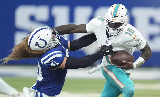 Miami Dolphins quarterback Tyler Huntley (18) blocks a tackle by Indianapolis Colts linebacker Grant Stuard (41) as he runs the ball during the first half of an NFL football game, Sunday, Oct. 20, 2024 in Indianapolis. (AP Photo/Michael Conroy)