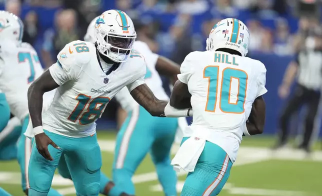 Miami Dolphins quarterback Tyler Huntley (18) hands off to wide receiver Tyreek Hill (10) during the first half of an NFL football game against the Indianapolis Colts, Sunday, Oct. 20, 2024 in Indianapolis. (AP Photo/Michael Conroy)