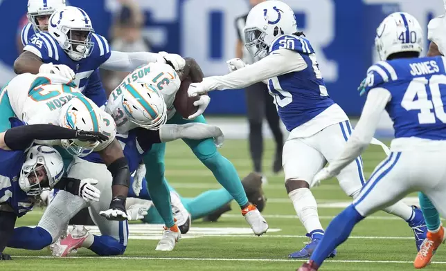 Indianapolis Colts linebacker Segun Olubi (50) strips the ball from Miami Dolphins running back Raheem Mostert (31) for a fumble recovered by Olubi during the second half of an NFL football game, Sunday, Oct. 20, 2024 in Indianapolis. (AP Photo/Michael Conroy)