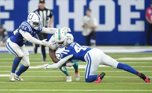 Indianapolis Colts linebacker Zaire Franklin (44) and cornerback Jaylon Jones (40) take down Miami Dolphins running back Raheem Mostert (31) during the first half of an NFL football game, Sunday, Oct. 20, 2024 in Indianapolis. (AP Photo/Michael Conroy)