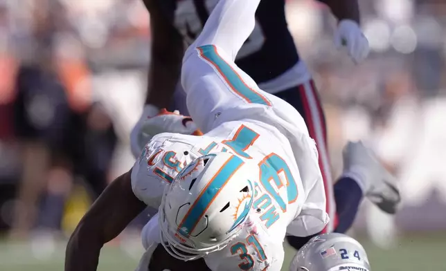 Miami Dolphins running back Raheem Mostert (31) is upended by New England Patriots safety Dell Pettus (24) during the second half of an NFL football game, Sunday, Oct. 6, 2024, in Foxborough, Mass. (AP Photo/Steven Senne)