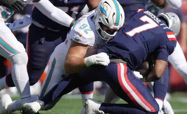 Miami Dolphins defensive tackle Zach Sieler (92) brings down New England Patriots quarterback Jacoby Brissett (7) during the first half of an NFL football game, Sunday, Oct. 6, 2024, in Foxborough, Mass. (AP Photo/Steven Senne)