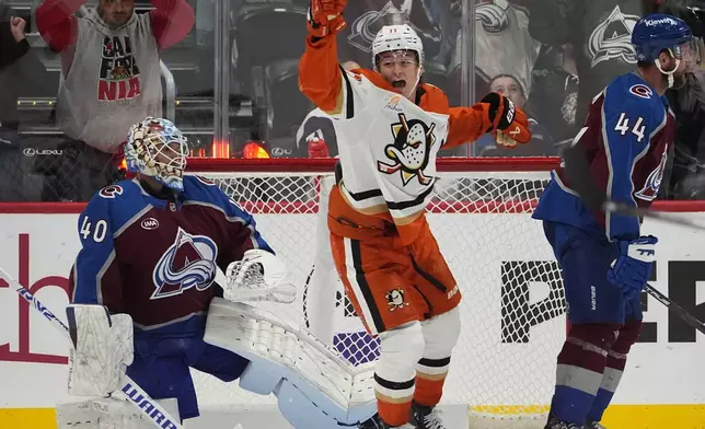 Anaheim Ducks center Trevor Zegras, center, reacts after right wing Troy Terry (not shown) scored against Colorado Avalanche goaltender Alexandar Georgiev, left, as Avalanche defenseman Calvin de Haan, right, skates away in the third period of an NHL hockey game Friday, Oct. 18, 2024, in Denver. (AP Photo/David Zalubowski)