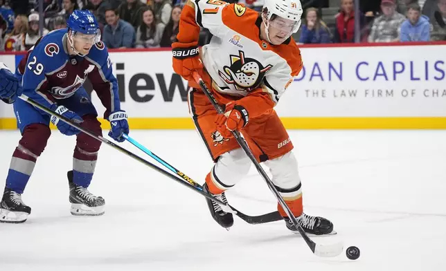 Anaheim Ducks center Leo Carlsson, right, drives with the puck past Colorado Avalanche center Nathan MacKinnon (29) in overtime of an NHL hockey game Friday, Oct. 18, 2024, in Denver. (AP Photo/David Zalubowski)