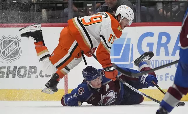 Anaheim Ducks right wing Troy Terry, top, jumps over Colorado Avalanche defenseman Cale Makar, bottom, in pursuit of the puck in overtime of an NHL hockey game Friday, Oct. 18, 2024, in Denver. (AP Photo/David Zalubowski)