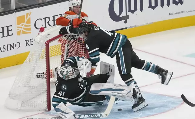 San Jose Sharks goaltender Vitek Vanecek, bottom, is knocked over by defenseman Cody Ceci (4) as Anaheim Ducks center Mason McTavish, top, watches during the third period of an NHL hockey game in San Jose, Calif., Saturday, Oct. 12, 2024. (AP Photo/Jeff Chiu)