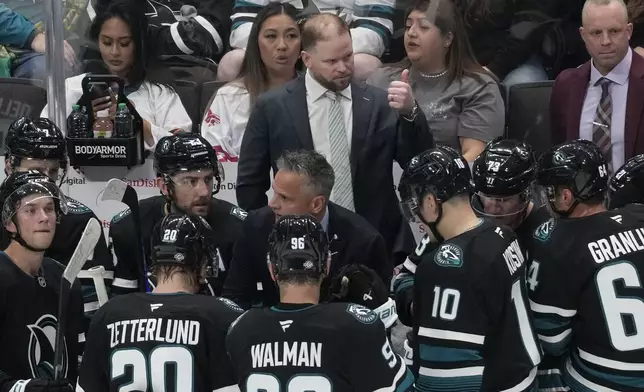 San Jose Sharks head coach Ryan Warsofsky, standing middle, gestures toward players during the third period of an NHL hockey game against the Anaheim Ducks in San Jose, Calif., Saturday, Oct. 12, 2024. (AP Photo/Jeff Chiu)