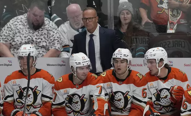 Anaheim Ducks head coach Greg Cronin, middle, stands behind players on the bench during the third period of an NHL hockey game against the San Jose Sharks in San Jose, Calif., Saturday, Oct. 12, 2024. (AP Photo/Jeff Chiu)