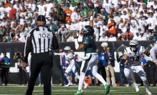 Philadelphia Eagles quarterback Jalen Hurts launches a long touchdown pass to wide receiver DeVonta Smith as Cincinnati Bengals defensive end Sam Hubbard (94) tries to stop him during the second half of an NFL football game, Sunday, Oct. 27, 2024 in Cincinnati. (AP Photo/Jeff Dean)