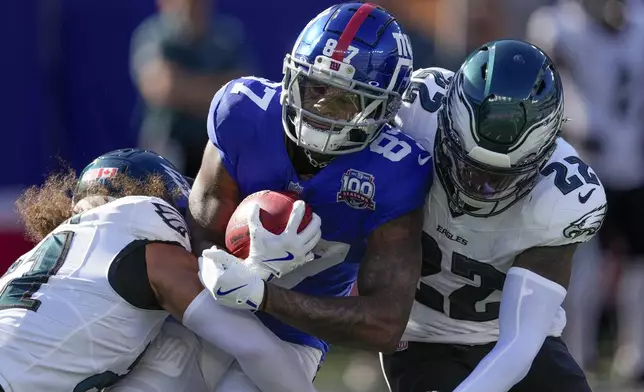 New York Giants wide receiver Ihmir Smith-Marsette (87) is tackled by Philadelphia Eagles safety Sydney Brown (21) and cornerback Kelee Ringo (22) during the third quarter of an NFL football game, Sunday, Oct. 20, 2024, in East Rutherford, N.J. (AP Photo/Seth Wenig)