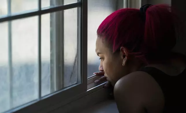 Gabriela Ramírez watches from a window as two of her friends try to repair her car Thursday, Aug. 29, 2024, in Aurora, Colo. (AP Photo/Godofredo A. Vásquez)