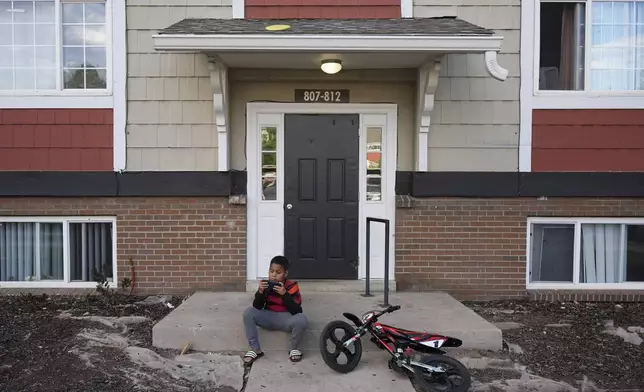 Dylan Martínez-Ramírez plays a game on his mother's cell phone outside their apartment Thursday, Aug. 29, 2024, in Aurora, Colo. (AP Photo/Godofredo A. Vásquez)