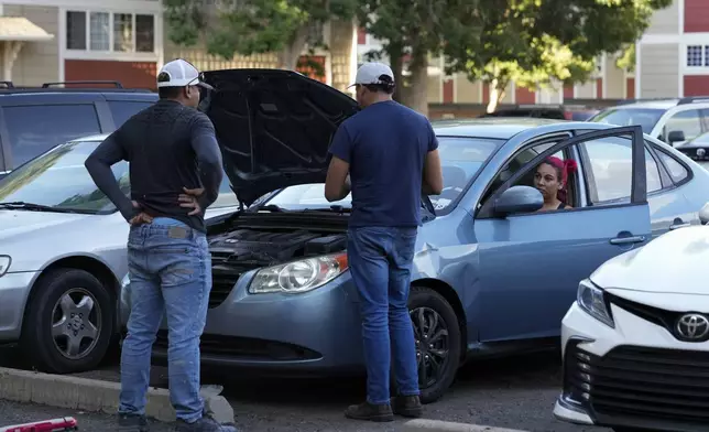 Gabriela Ramírez, right, and her boyfriend Ronexi Bocaranda, left, listen as mechanic diagnoses issues with Gabriela's car Thursday, Aug. 29, 2024, in Aurora, Colo. (AP Photo/Godofredo A. Vásquez)