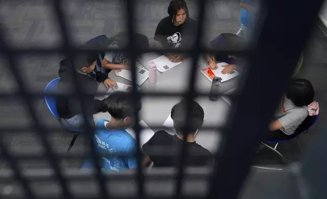 Alisson Ramírez, top center, watches as classmates collaborate on a math worksheet Wednesday, Aug. 28, 2024, in Aurora, Colo. (AP Photo/Godofredo A. Vásquez)