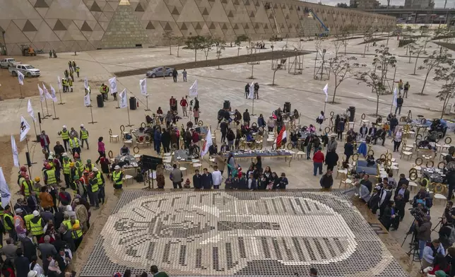 FILE - Visitors walk past the cups used in the mosaic of ancient Egyptian King Tutankhamun's mask at the yard of the Grand Egyptian Museum near the Great Pyramids of Giza, Egypt, Saturday, Dec. 28, 2019. (AP Photo/Hamada Elrasam, File)