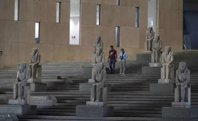 Visitors walk past ancient Egyptian statues along the Grand Staircase at the Grand Egyptian Museum in Giza, Egypt, Tuesday, Oct.15, 2024. (AP Photo/Khaled Elfiqi)