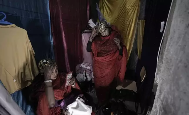 Sudanese Camirata troupe dancers Hoda Othman, right, and Amal Soliman put makeup on before their show at the Russian culture center in Cairo, Egypt, Sunday, Sept. 15, 2024. (AP Photo/Amr Nabil)