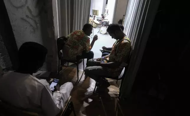 Sudanese Camirata troupe members chat with their families on mobile phones before their show at the Russian culture center in Cairo, Egypt, Sunday, Sept. 15, 2024. (AP Photo/Amr Nabil)