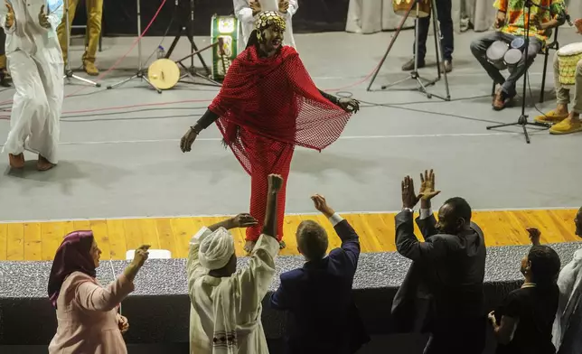 Sudanese Camirata troupe dancer Hoda Othman, performs a dance from Central Sudan, "Al-Arda", as Sudanese and foreign audience react during a show at the Russian culture center in Cairo, Egypt, Sunday, Sept. 15, 2024. (AP Photo/Amr Nabil)