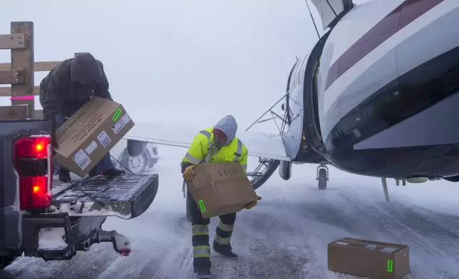 In blizzard winds, Lee Kayotuk, center, helps unload cargo from the one flight of the day in and out of the village in Kaktovik, Alaska, Thursday, Oct. 17, 2024. (AP Photo/Lindsey Wasson)