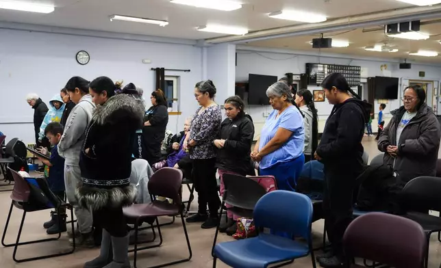 Community members bow their heads for a prayer during a "singspiration" community event at the village community center in Kaktovik, Alaska, Monday, Oct. 14, 2024. (AP Photo/Lindsey Wasson)