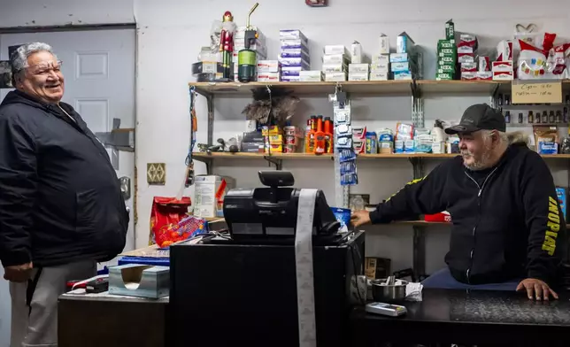 George Kaleak, left, whaling captain and deputy advisor to the North Slope Borough mayor, talks with cashier Kent Sims, right, at Sims Store, one of two small grocery stores in the village in Kaktovik, Alaska, Tuesday, Oct. 15, 2024. (AP Photo/Lindsey Wasson)