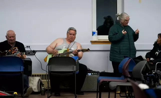 George Kaleak, center in grey, whaling captain and deputy advisor to the North Slope Borough mayor, plays guitar during a "singspiration" community event to honor his late mother at the village community center in Kaktovik, Alaska, Monday, Oct. 14, 2024. (AP Photo/Lindsey Wasson)