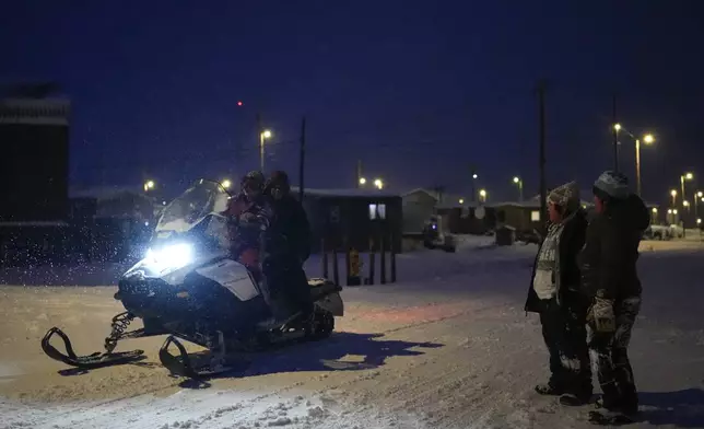 Children stop to talk with friends on a snowmobile as they play in the snow after school in the village of Kaktovik, Alaska, Wednesday, Oct. 16, 2024. (AP Photo/Lindsey Wasson)