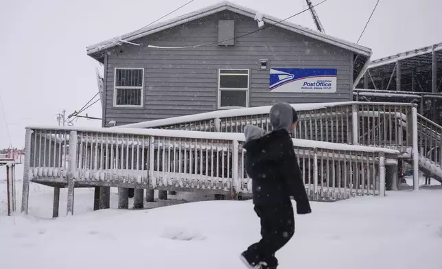 A resident walks with their child past the village's post office in Kaktovik, Alaska, Wednesday, Oct. 16, 2024. (AP Photo/Lindsey Wasson)