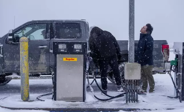 Edwin Solomon, 18, right, stands in the wind and snow while filling up a truck with regular gas at a price of $7.50 a gallon in Kaktovik, Alaska, Wednesday, Oct. 16, 2024. (AP Photo/Lindsey Wasson)