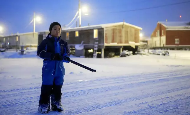 Johnny, 7, holds his pellet gun for warding away polar bears as he goes out to play with other children after school in Kaktovik, Alaska, Wednesday, Oct. 16, 2024. (AP Photo/Lindsey Wasson)