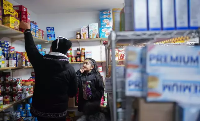 Chloe Gordon, 9, looks at her mother, Amanda Toorak, left, as they shop for packaged goods at Sims Store, one of two small stores in the village in Kaktovik, Alaska, Tuesday, Oct. 15, 2024. (AP Photo/Lindsey Wasson)