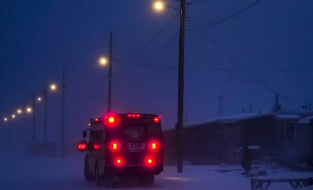 A child walks to the village's school bus as a blizzard blows outside in Kaktovik, Alaska, Thursday, Oct. 17, 2024. (AP Photo/Lindsey Wasson)