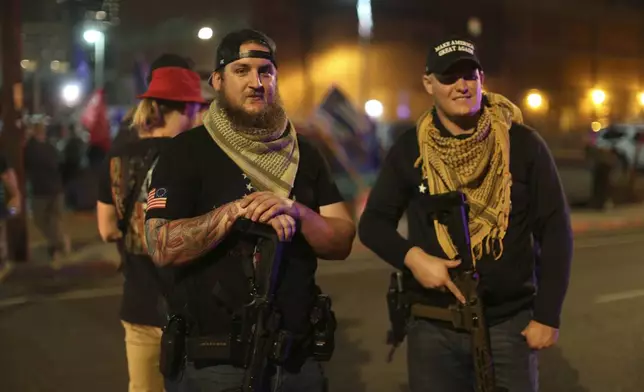 FILE - Armed supporters of President Donald Trump stand outside the Maricopa County Recorder's Office where votes in the general election are being counted, in Phoenix, Nov. 6, 2020. The man at left, who did not want to give his name, says he came armed to the pro-Trump protest to "exercise his common Second Amendment right." (AP Photo/Dario Lopez-MIlls, File)