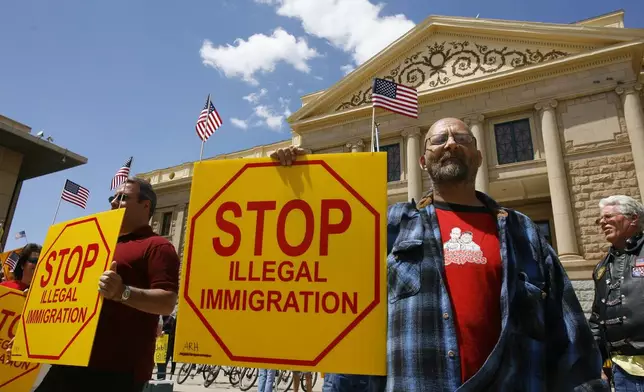 FILE - Ernie Getford holds a sign in support of the controversial SB1070 illegal immigration enforcement bill during a rally at the state Capitol in Phoenix, April 23, 2010. (Nick Oza/The Arizona Republic via AP, File)