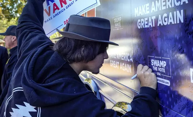 Former President Trump supporter, Tyler Schultz of Rutherfordton signs the tour bus during the Team Trump bus tour across North Carolina, Thursday, Oct. 17, 2024 in Rutherfordton, N.C. (AP Photo/Kathy Kmonicek)