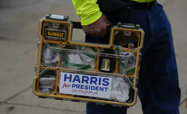 James Eckstein who is campaigning for Democratic presidential nominee Vice President Kamala Harris, holds is organizer containing sticker and buttons at the Butler Fall Festival in Butler, Saturday, Sept. 28, 2024. (AP Photo/Matt Rourke)