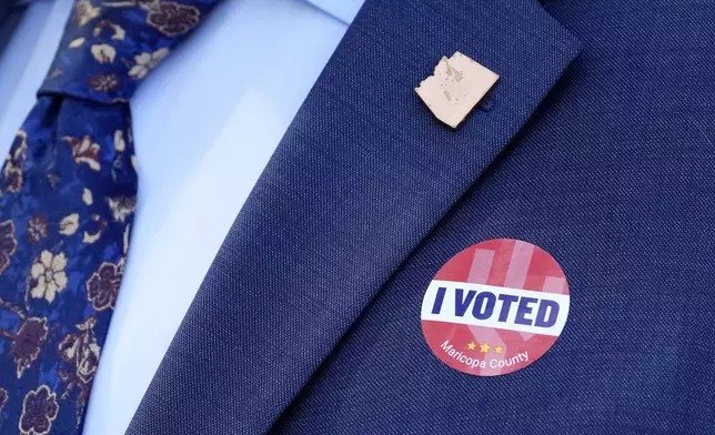 Arizona Secretary of State Adrian Fontes wears an Arizona state pin and an "I Voted" sticker after leaving Surprise City Hall after voting on the first day of early in-person voting for the general election Wednesday, Oct. 9, 2024, in Surprise, Ariz. (AP Photo/Ross D. Franklin)