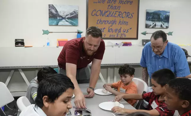 Trevor Cowling helps out during an activity class at a summer camp for youth at Valley Baptist Church Tuesday, June 18, 2024, in Mesa, Ariz. (AP Photo/Ross D. Franklin)