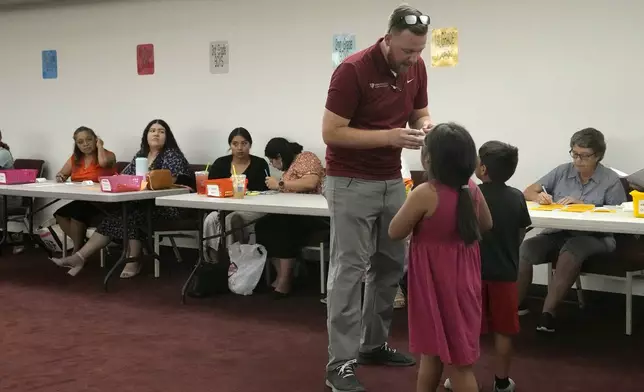 Trevor Cowling helps participants in summer camp find their classes at Valley Baptist Church Tuesday, June 18, 2024, in Mesa, Ariz. (AP Photo/Ross D. Franklin)