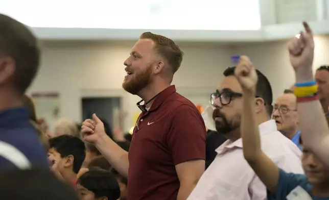 Trevor Cowling, left, and Karl Peterson, right, participate in a service during a summer camp for youth at Valley Baptist Church, Tuesday, June 18, 2024, in Mesa, Ariz. (AP Photo/Ross D. Franklin)