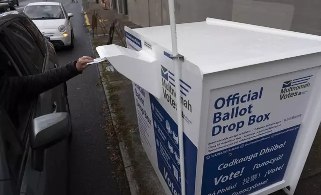 A person drops off their 2024 election ballot at a newly installed drop box outside the Multnomah County Elections Division office on Monday, Oct. 28, 2024, in Portland, Ore. (AP Photo/Jenny Kane)