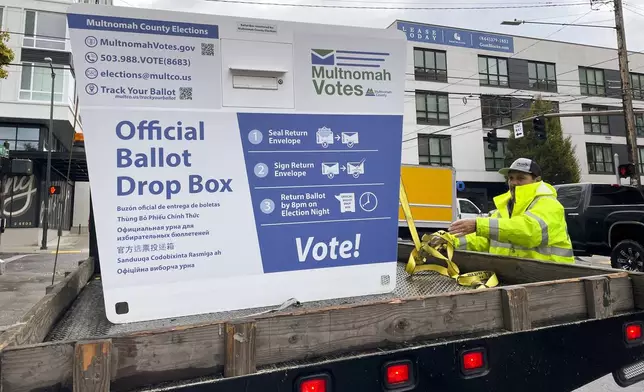 A replacement ballot drop box is unloaded on Monday, Oct. 28, 2024, in Portland, Ore. The Portland Police Bureau reported that officers and firefighters responded to a fire in one ballot drop box on Monday morning. (AP Photo/Claire Rush)