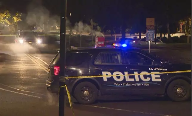 In this image made from a video provided by KGW8, authorities investigate smoke pouring out of a ballot box on Monday, Oct. 28, 2024, in Vancouver, Wash. (KGW8 via AP)