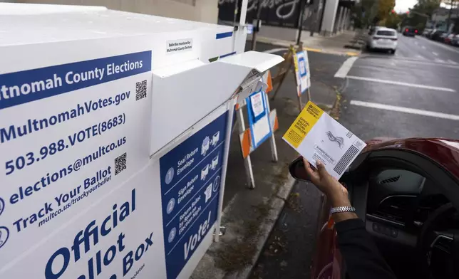 A voter drops off a ballot for the 2024 election in a newly installed drop box at the Multnomah County Elections Division office on Monday, Oct. 28, 2024, in Portland, Ore., after the pervious drop box was damaged. (AP Photo/Jenny Kane)