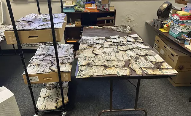 In this image provided by the Clark County Auditor's Office, ballots damaged in a drop box arson in Vancouver, Wash., are spread on tables on Monday, Oct. 28, 2024. (Greg Kimsey/Clark County Auditor's Office via AP)