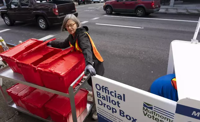 Election workers collect ballots from a newly placed ballot drop box outside the Multnomah County Elections Division office on Monday, Oct. 28, 2024, in Portland, Ore. (AP Photo/Jenny Kane)